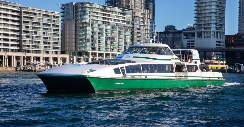 A Supercat vessel cruising in Sydney Harbour with buildings in the background